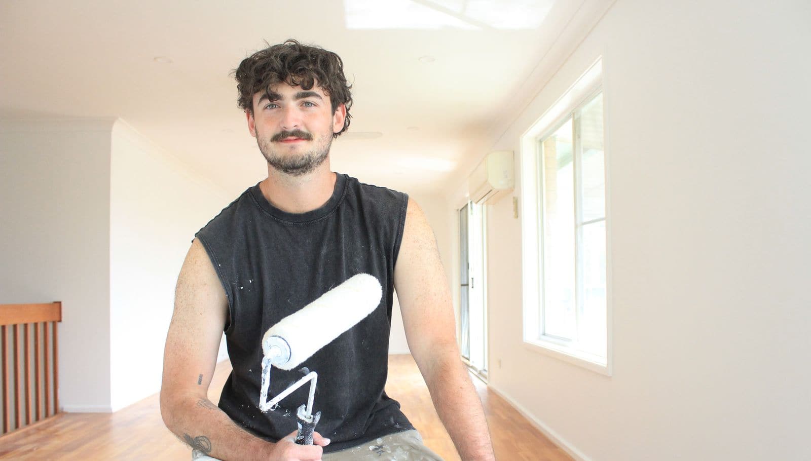Dylan, owner of Pristine Coat Painting, holding a paint roller on a job