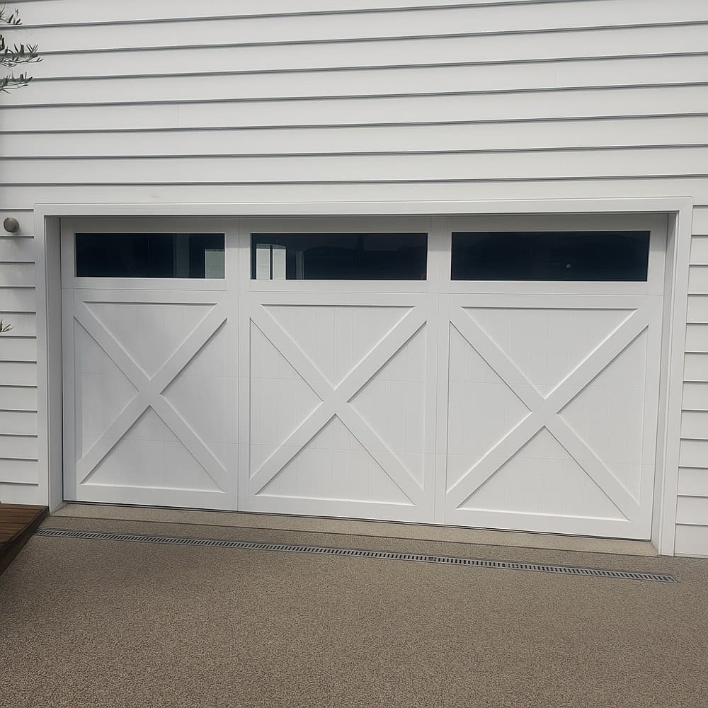 Newly painted white garage door set in weatherboard cladding